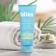 Bliss tube beside ruler and toes for scale, showing 4 fl oz size and real-world comparison