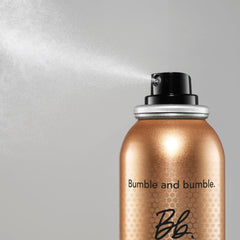 Model using Bumble and bumble Heat Shield while blow-drying hair, demonstrating faster styling benefit