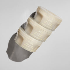Oribe Fiber Groom texture close-up on fingers demonstrating creamy, flexible paste for control