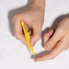 Tweezerman beside a coin to show compact size and portable convenience