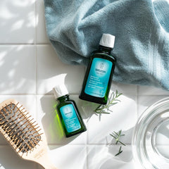 Weleda revitalizing hair tonic held in hand to show 100 ml size and travel benefit