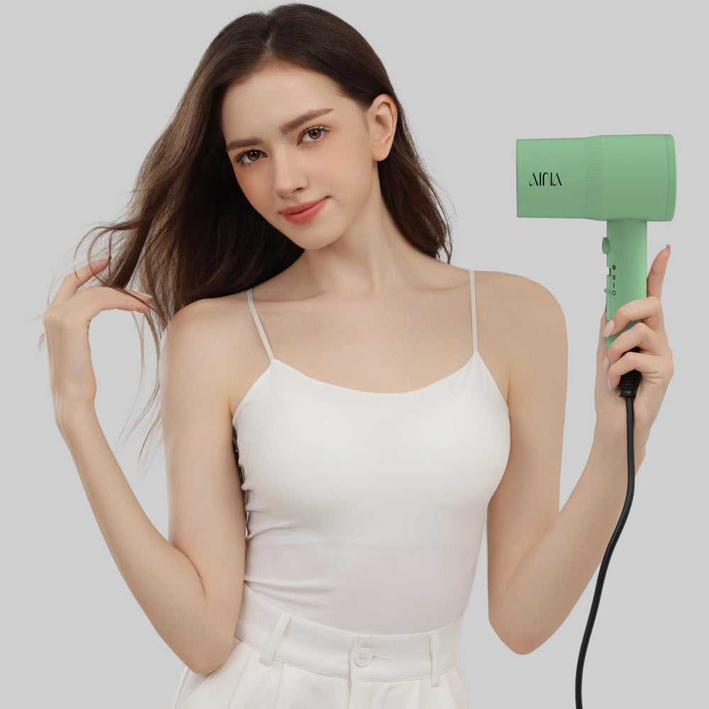 AINA dryer next to hand showing compact scale and comfortable grip benefit
