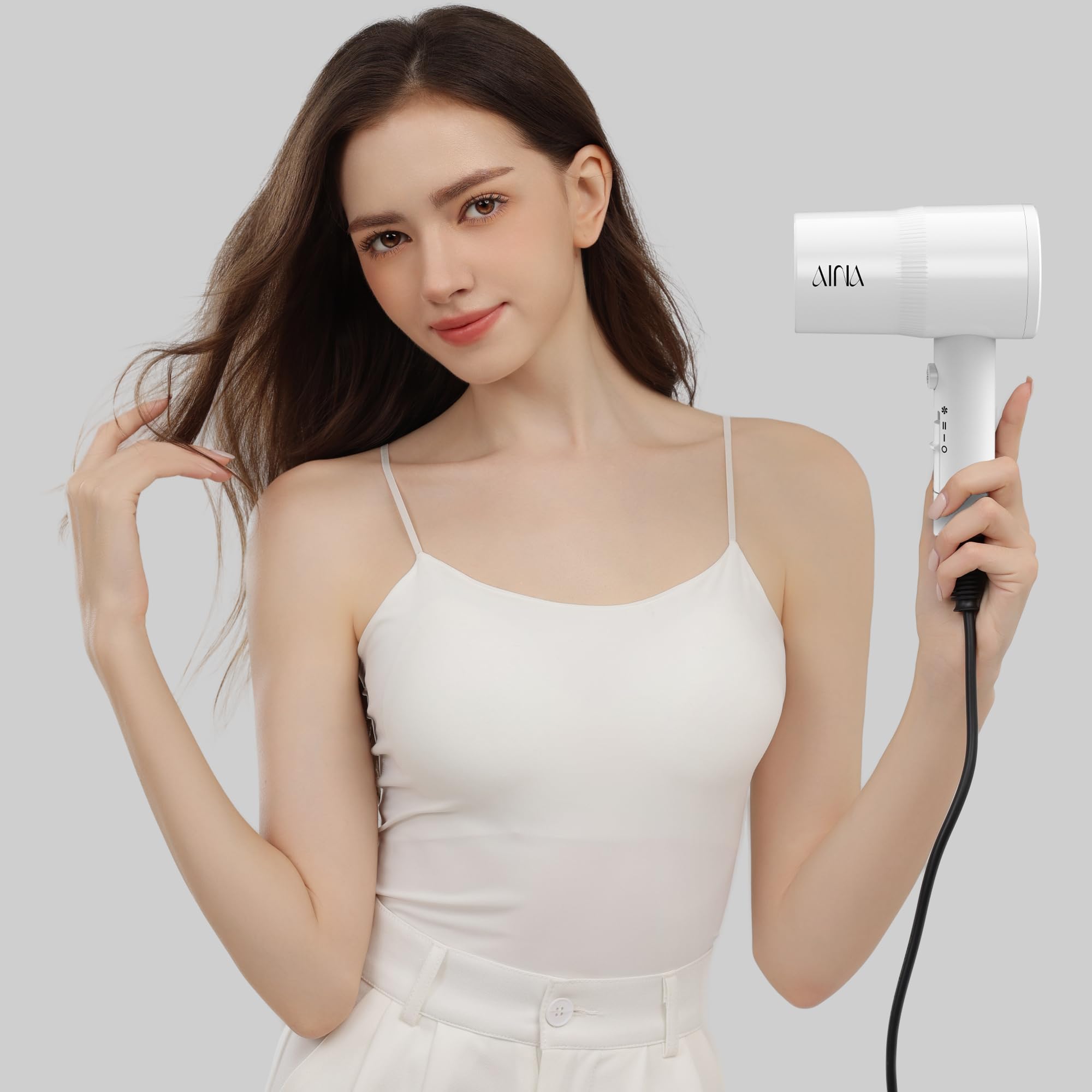 AINA hair dryer next to a ruler for size and scale, convenient for travel
