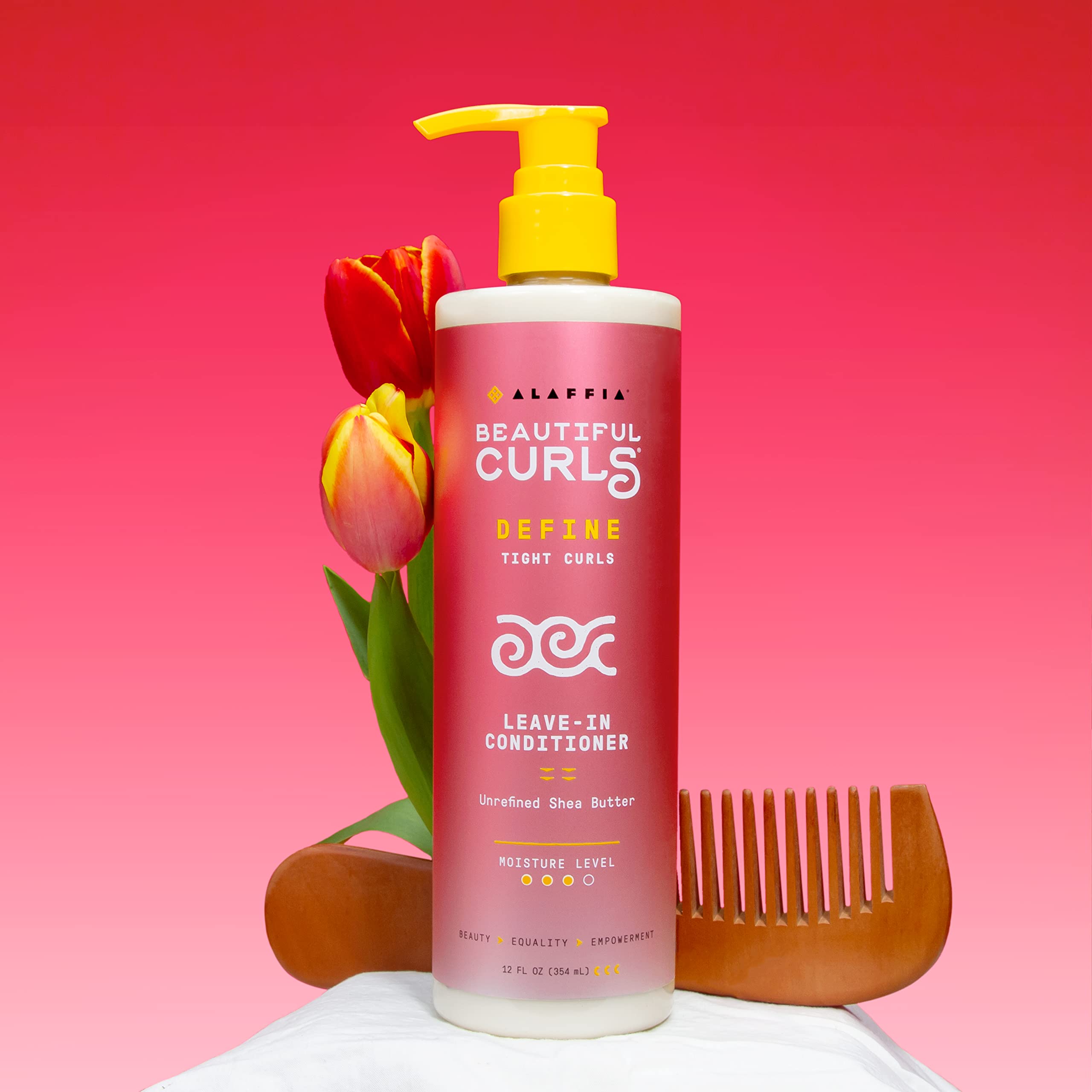 Alaffia leave-in applied to damp hair in hands aiding smoother combing