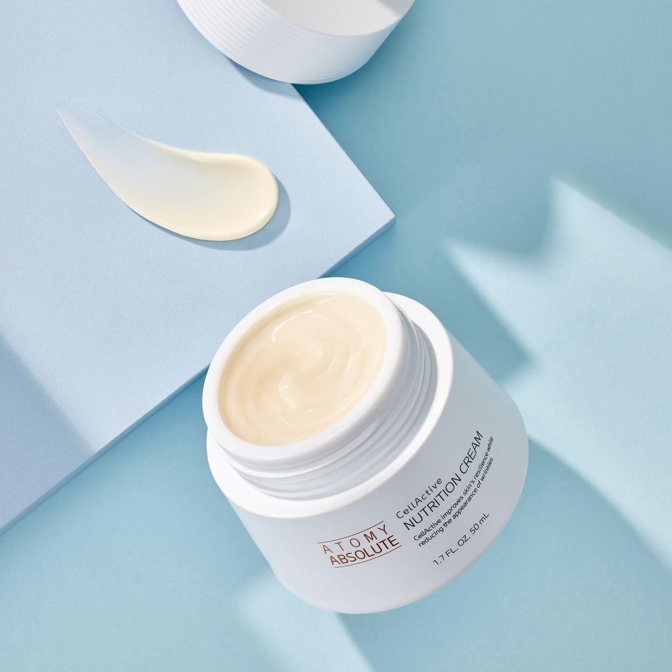 Atomy Absolute CellActive cream texture on a spoon close-up, shows smooth absorbent consistency