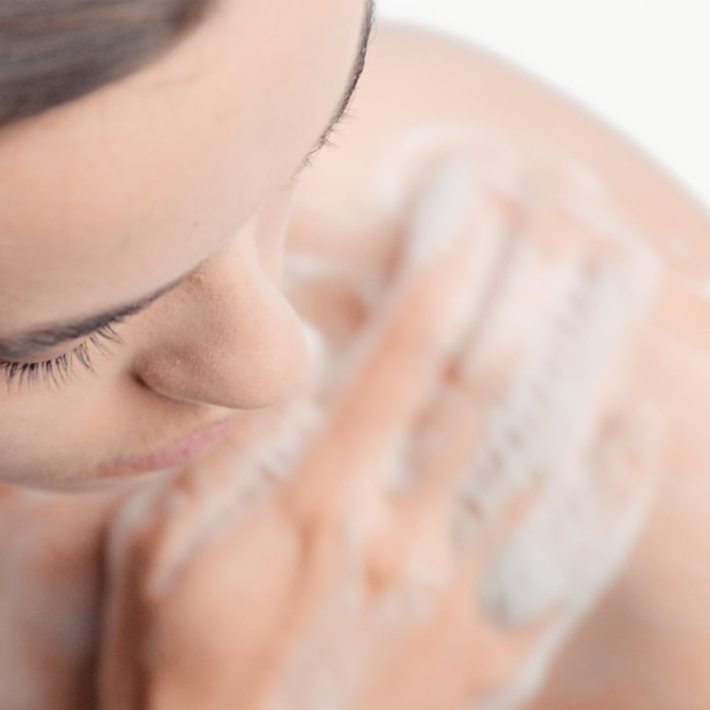 Person using Bioderma Atoderm on legs demonstrating body cleansing comfort