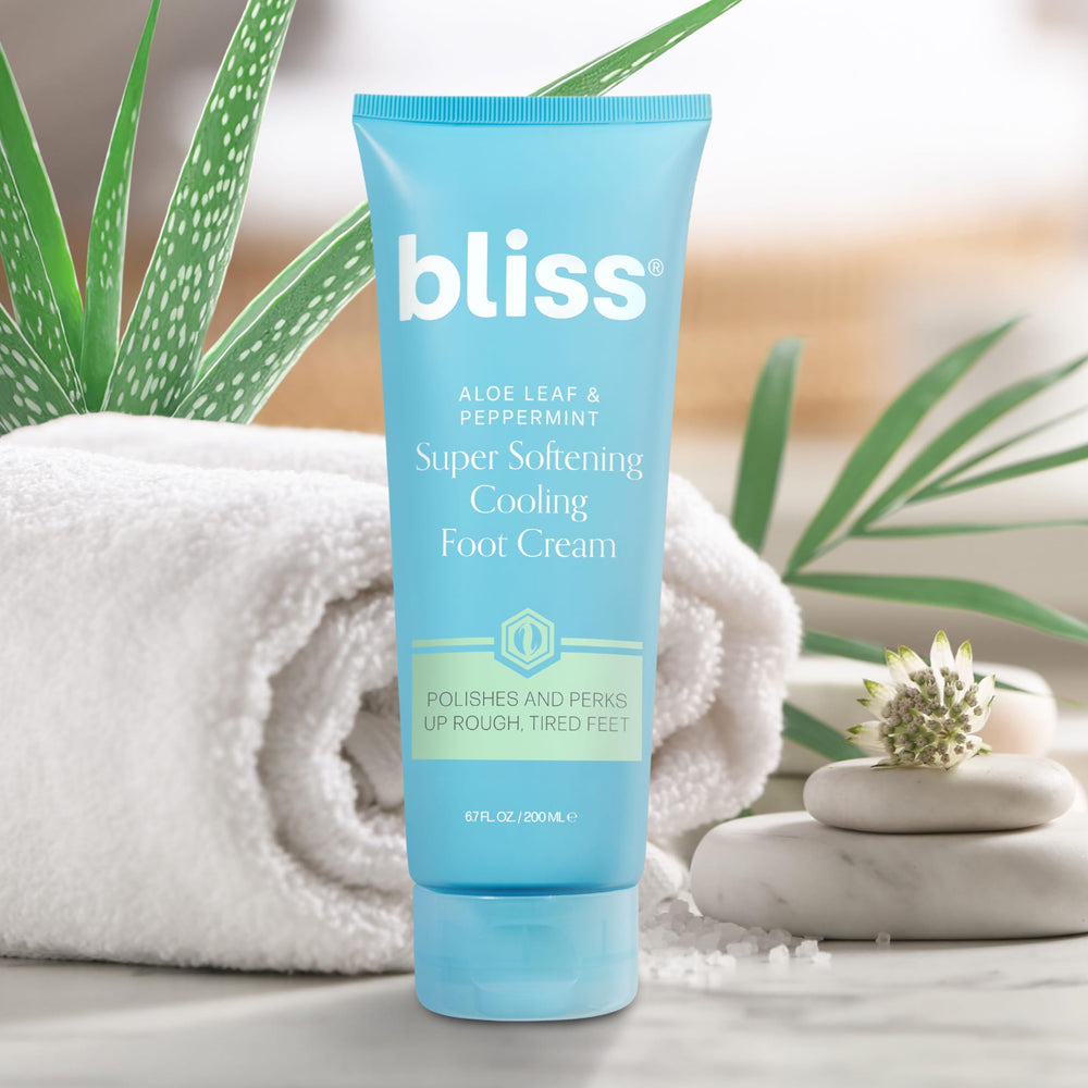Bliss tube beside ruler and toes for scale, showing 4 fl oz size and real-world comparison