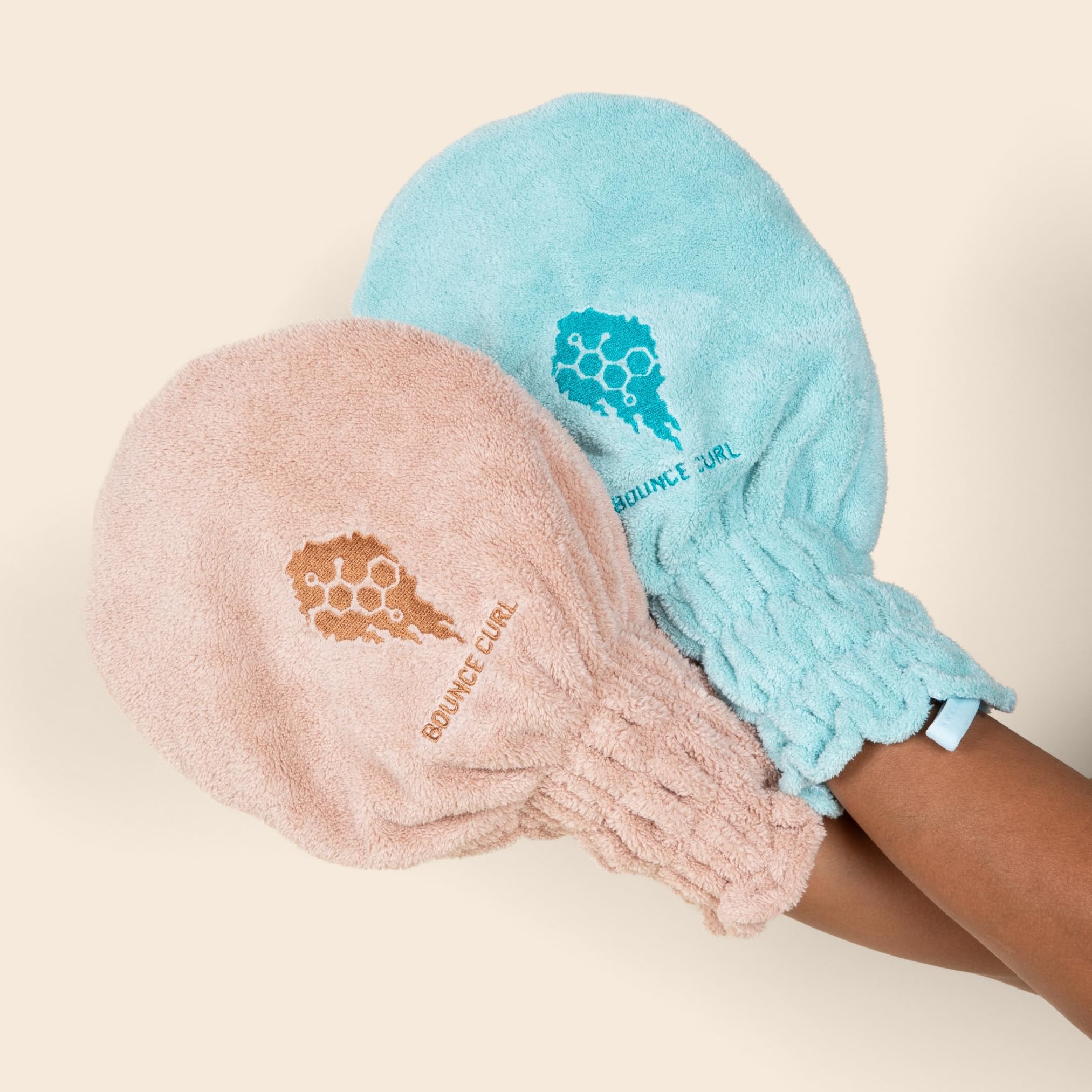 Bounce Curl mitt next to hand for scale showing portable size benefit