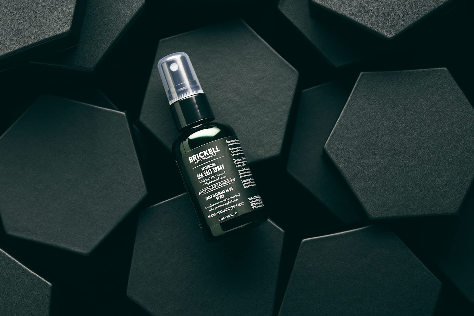 Brickell Men’s spray texture in hand demonstrating gritty, touchable hold