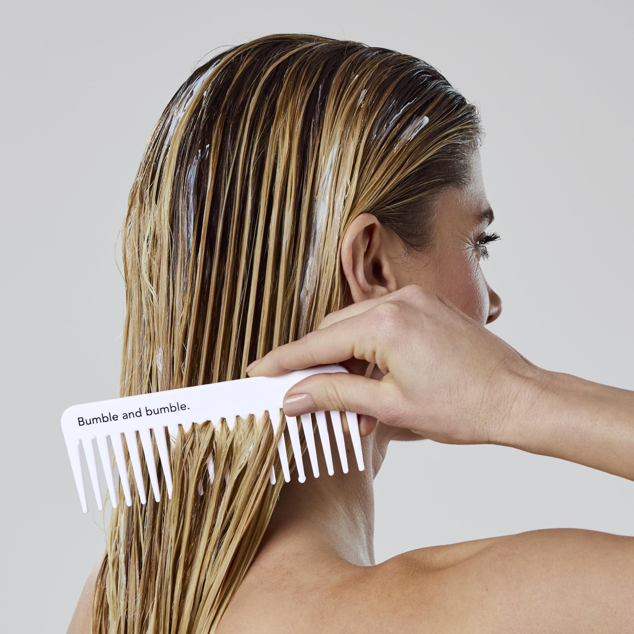 Bumble and bumble conditioner in hand for scale, shows compact travel convenience benefit