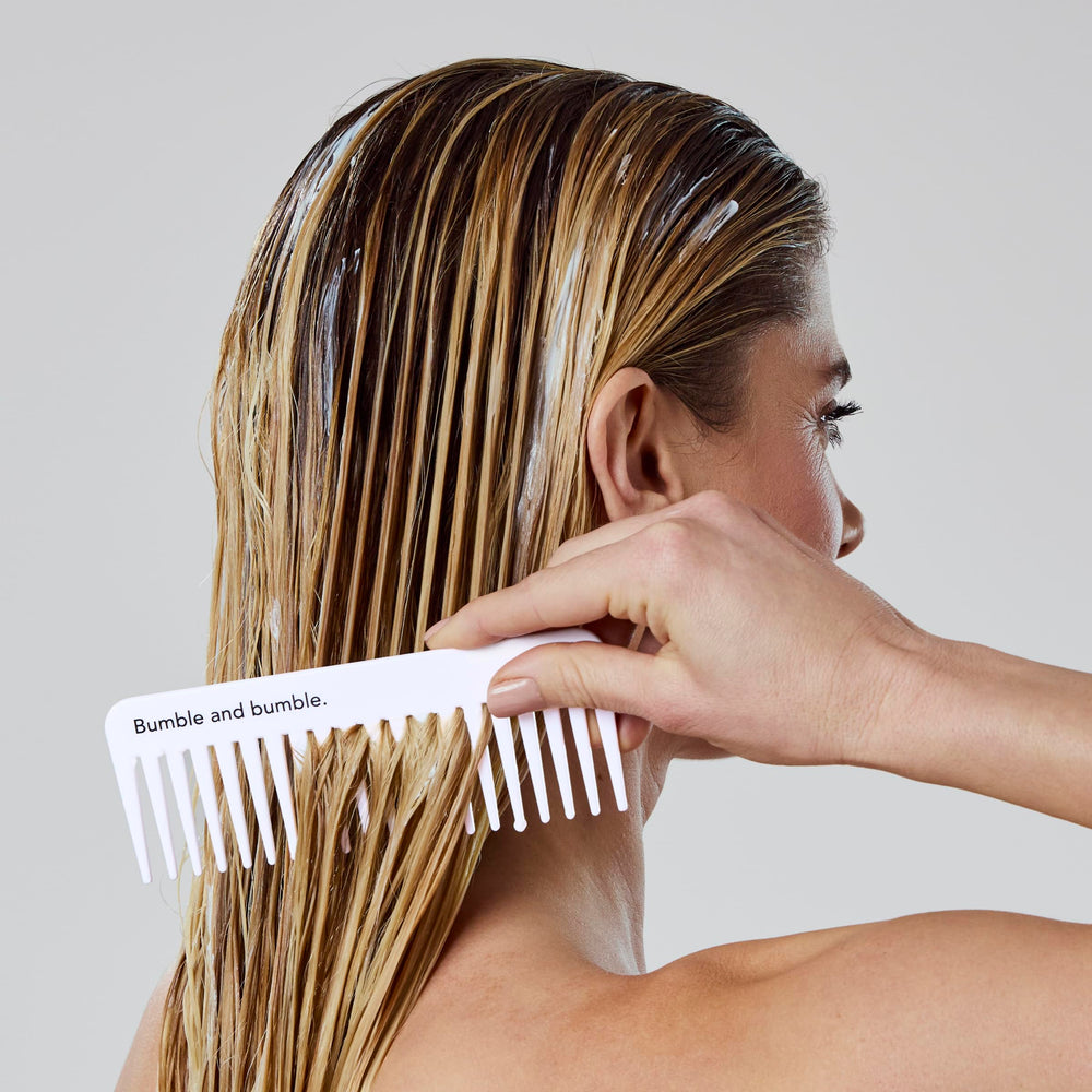 Bumble and bumble conditioner in hand for scale, shows compact travel convenience benefit