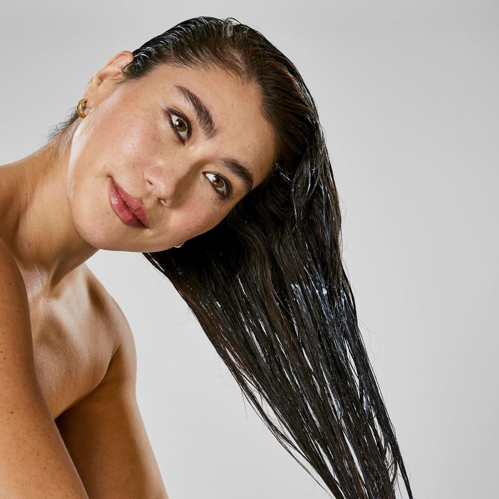 Bumble and bumble mask being applied to damp hair to demonstrate frizz control