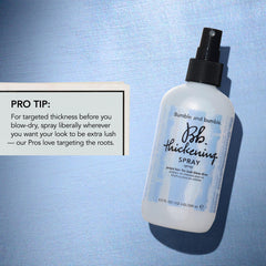Bumble and bumble applying spray at roots to create lift and targeted volume benefit