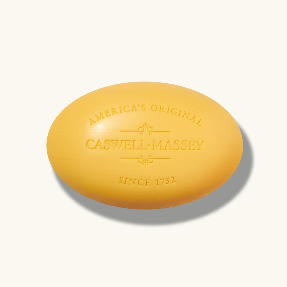 Caswell-Massey bar next to hand showing 5.8 oz size and scale