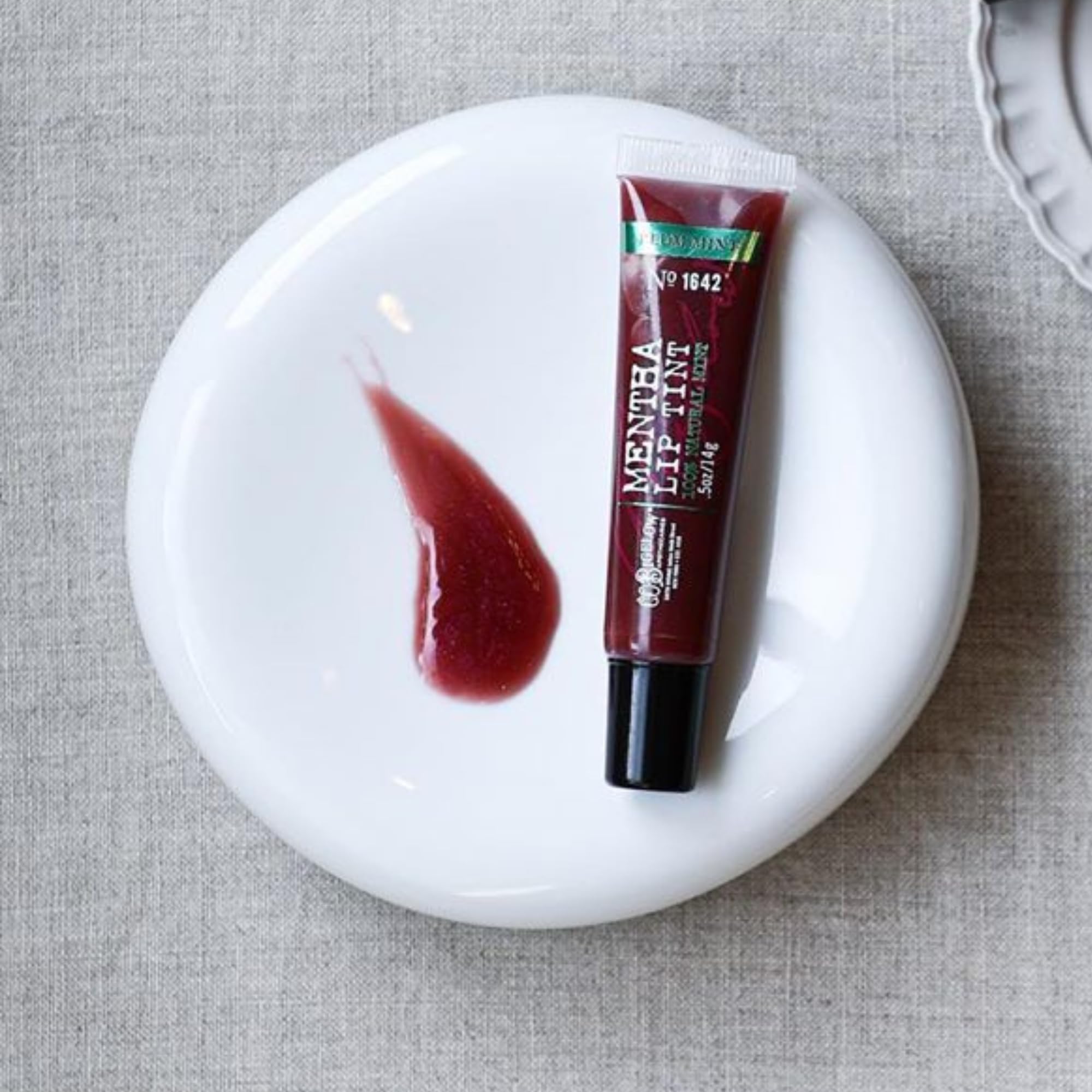 C. O. Bigelow application on lips showing sheer plum tint and luminous finish
