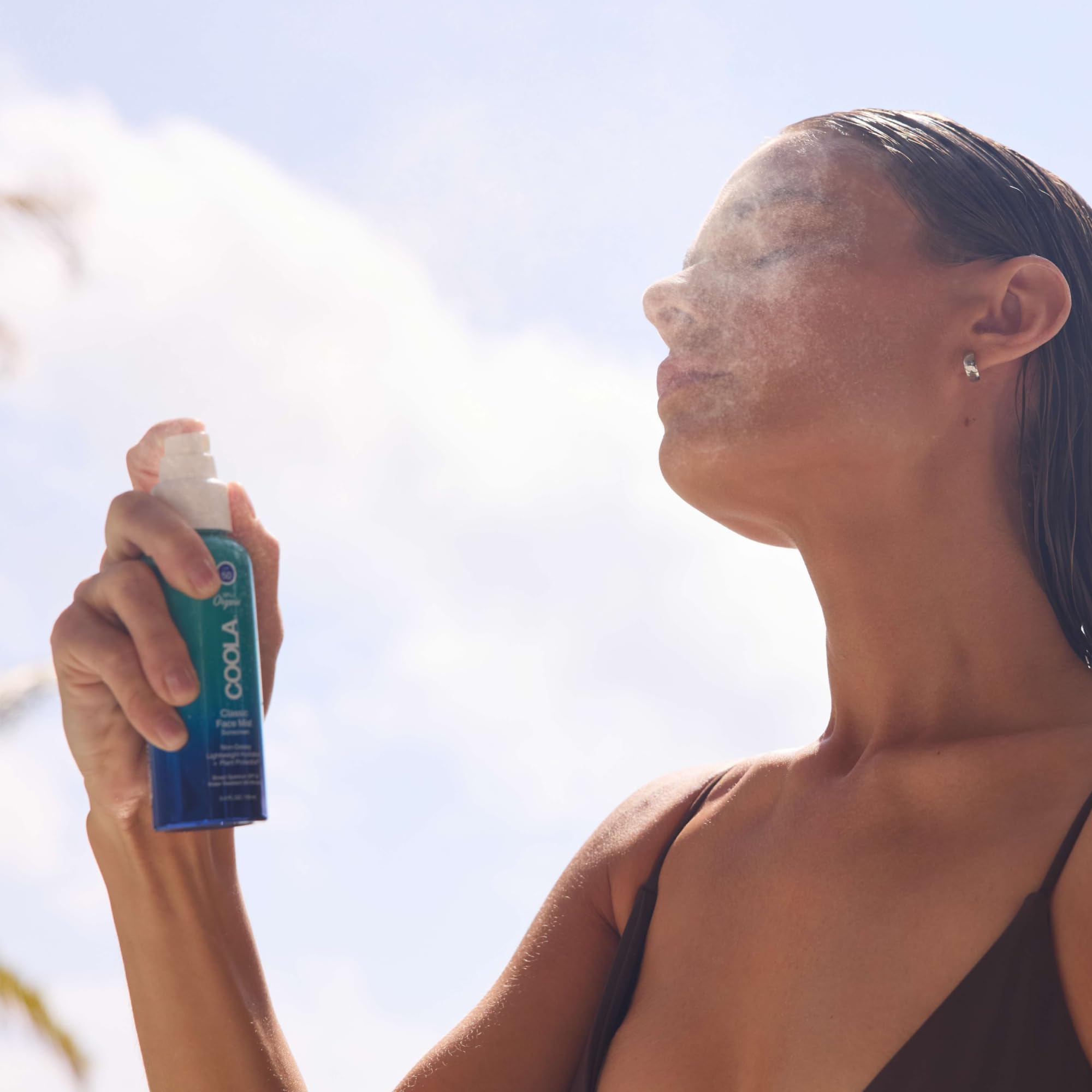 COOLA bottle in hand to show 3.4 fl oz scale and portable convenience