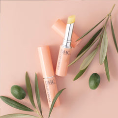 DHC lip cream texture on finger demonstrating creamy spreadable hydration
