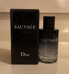 Dior Sauvage mini open splash pouring onto wrist — precise travel application