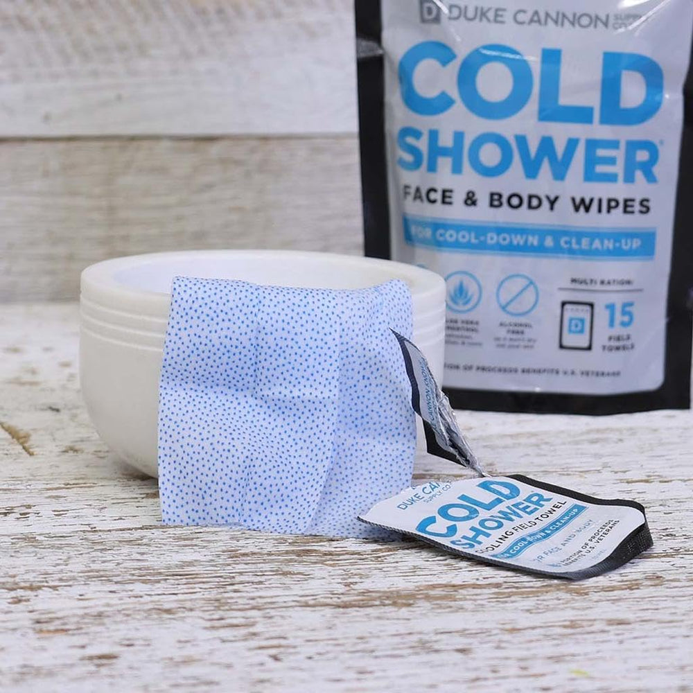 Hand holding single Duke Cannon cooling towel to show compact, travel-friendly scale