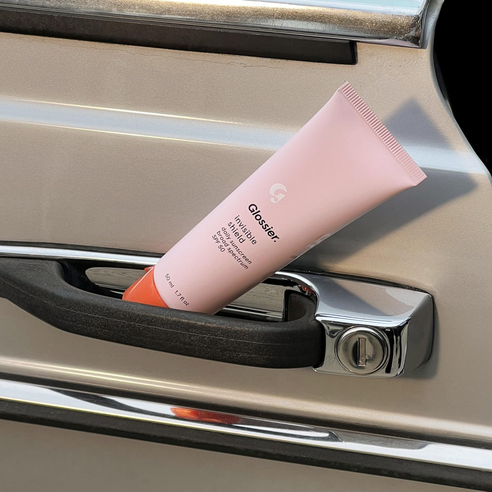 Glossier Invisible Shield being applied before makeup in a vanity routine benefit: primes skin for foundation