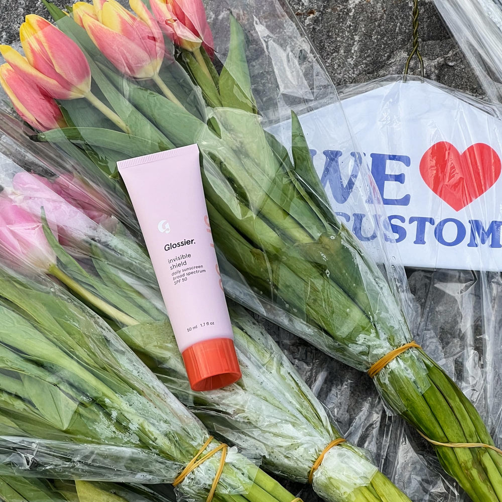 Glossier Invisible Shield used outdoors in city setting showing lifestyle wear benefit: daily broad-spectrum protection