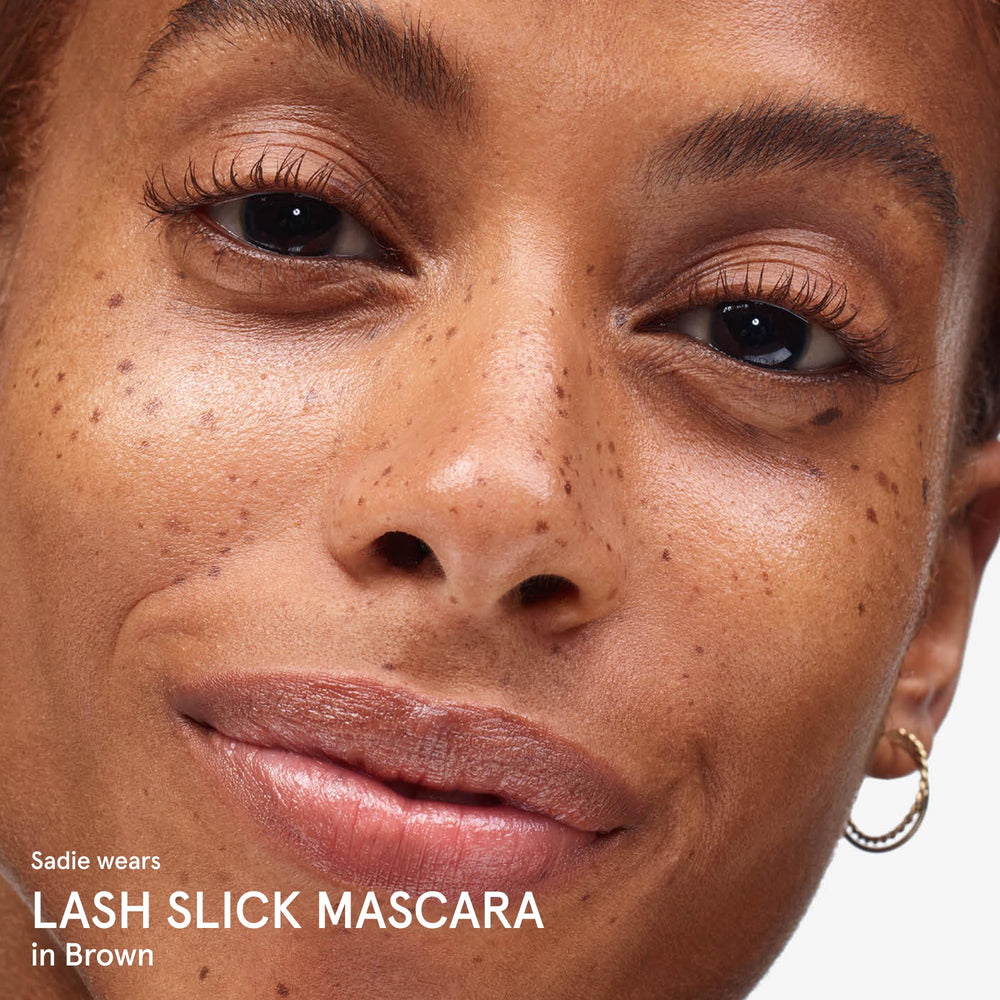 Glossier Lash Slick next to ruler scale showing compact size and travel-friendly benefit