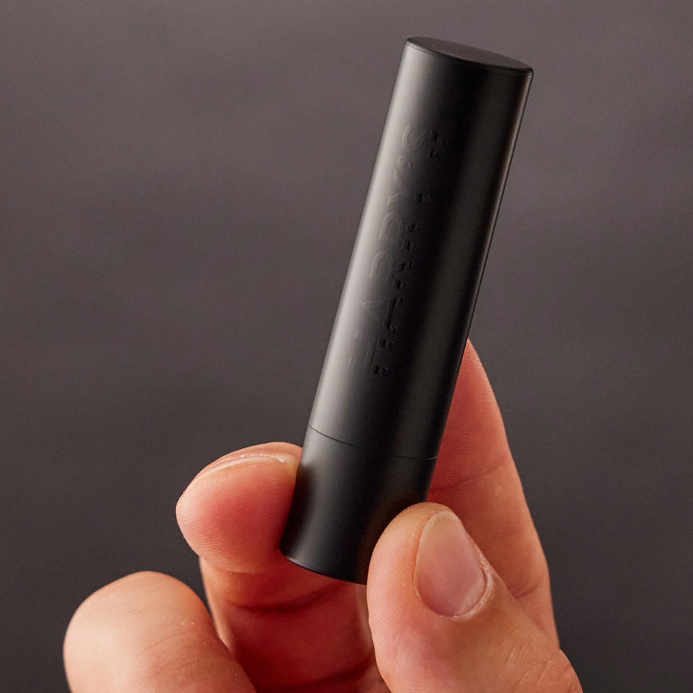 Harry's balm beside a coin to show compact size and easy portability benefit