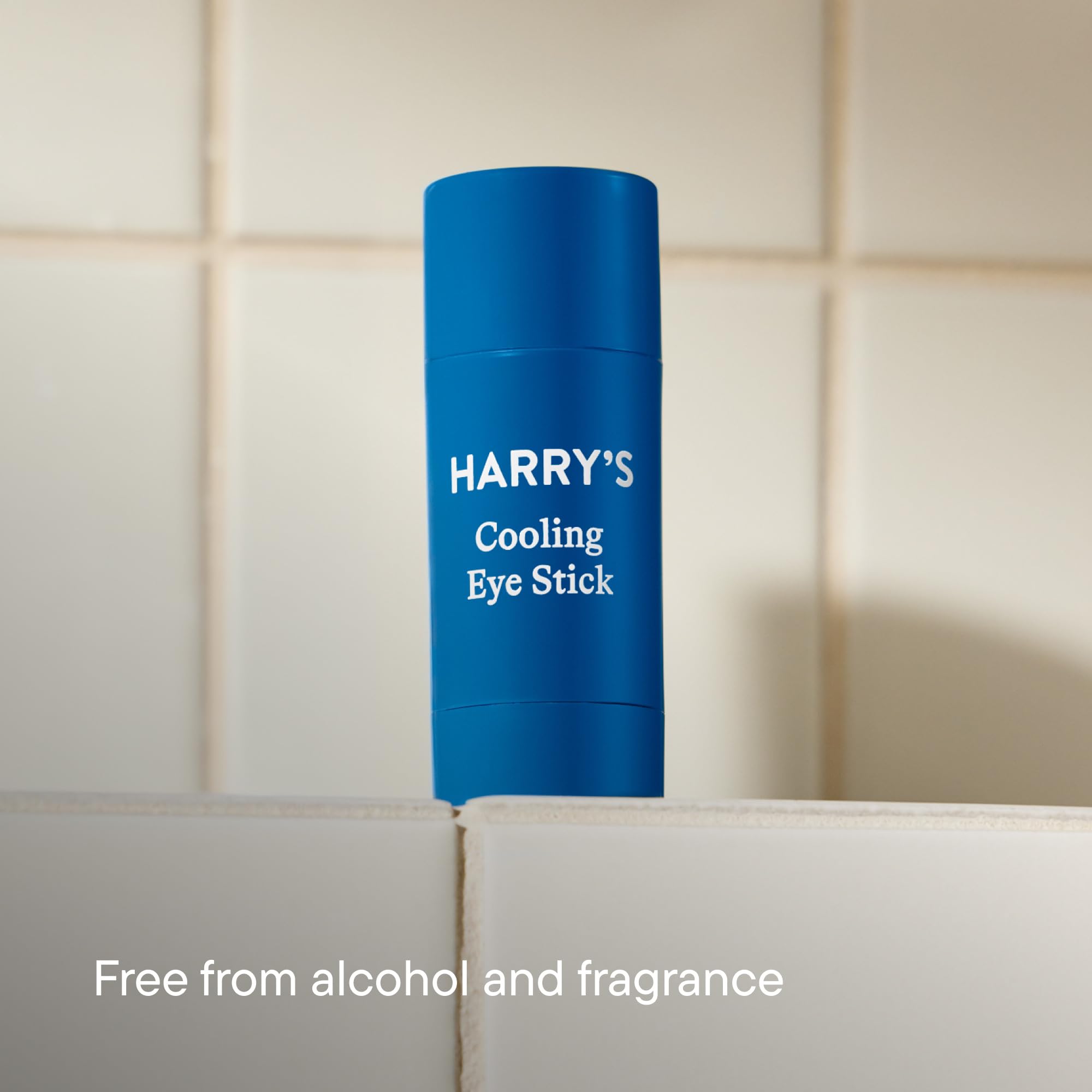 Harry's cooling eye stick next to a credit card for scale showing compact travel-friendly size