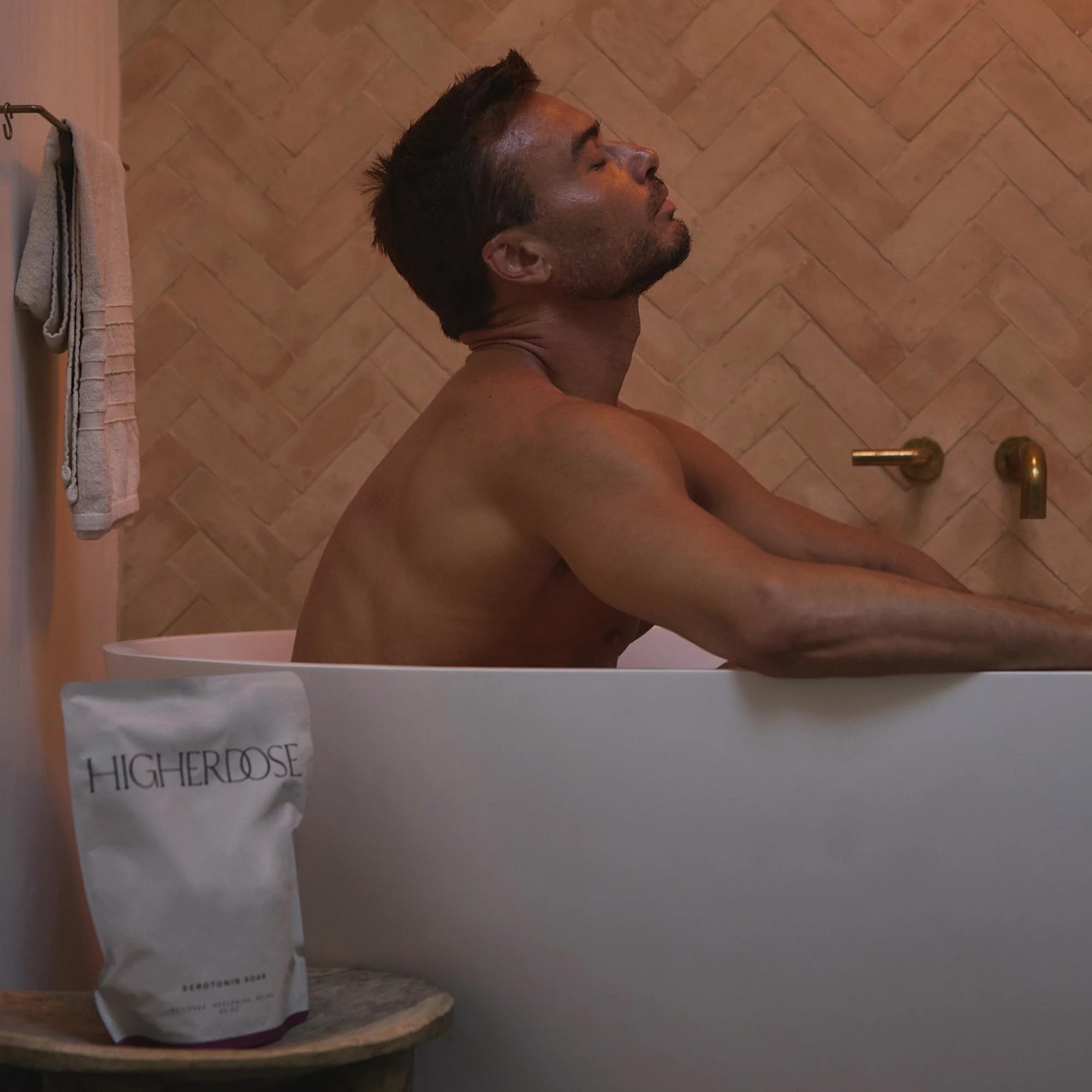 HigherDOSE scooping salts at tub edge showing simple ritual preparation
