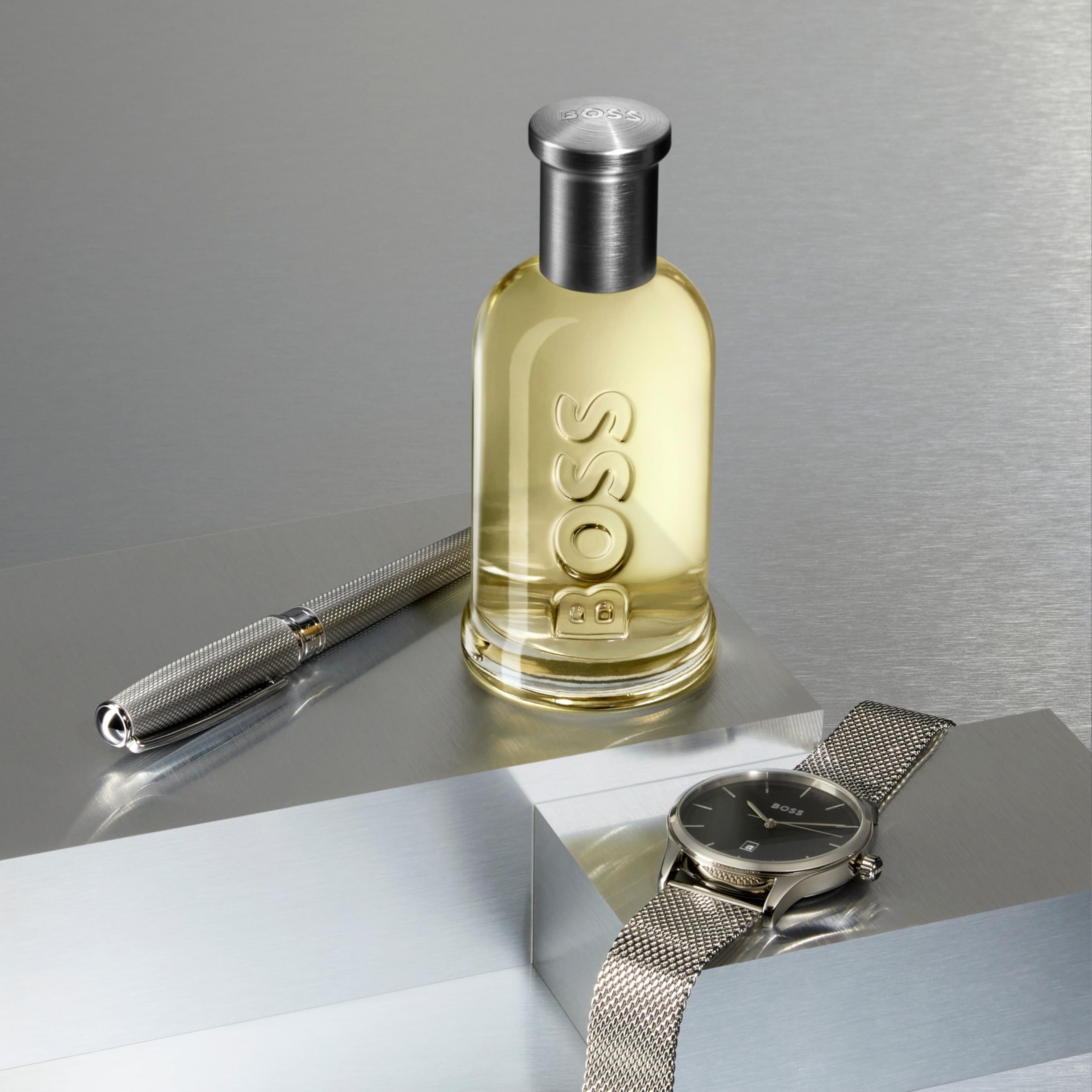 Arrangement of apple, cinnamon sticks and wood elements beside Hugo Boss bottle, indicates scent notes
