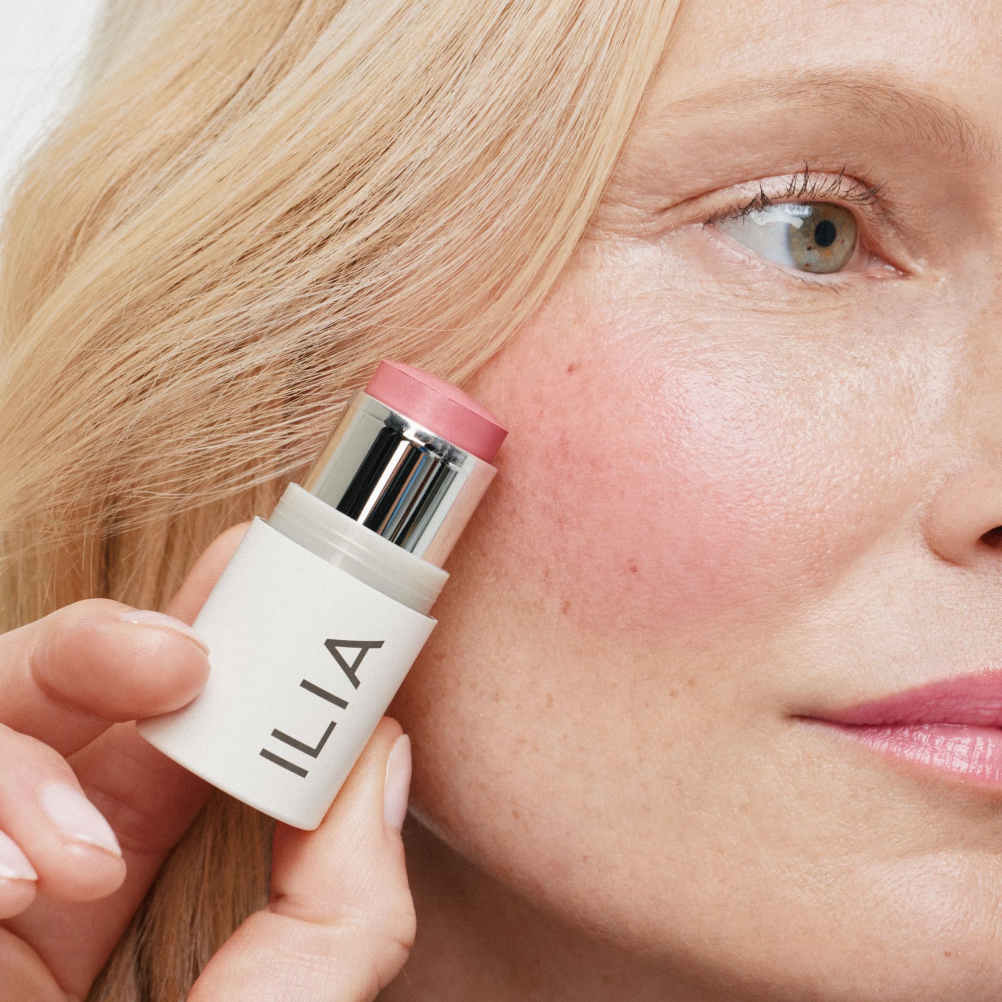 ILIA applying multi-stick to cheek showing easy blending and luminous benefit