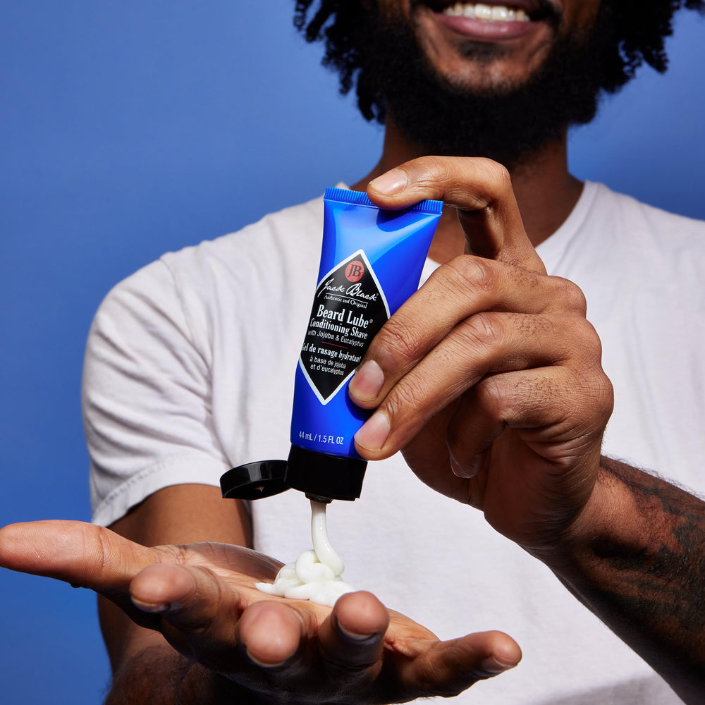 Jack Black Beard Lube next to razor for size comparison and travel convenience