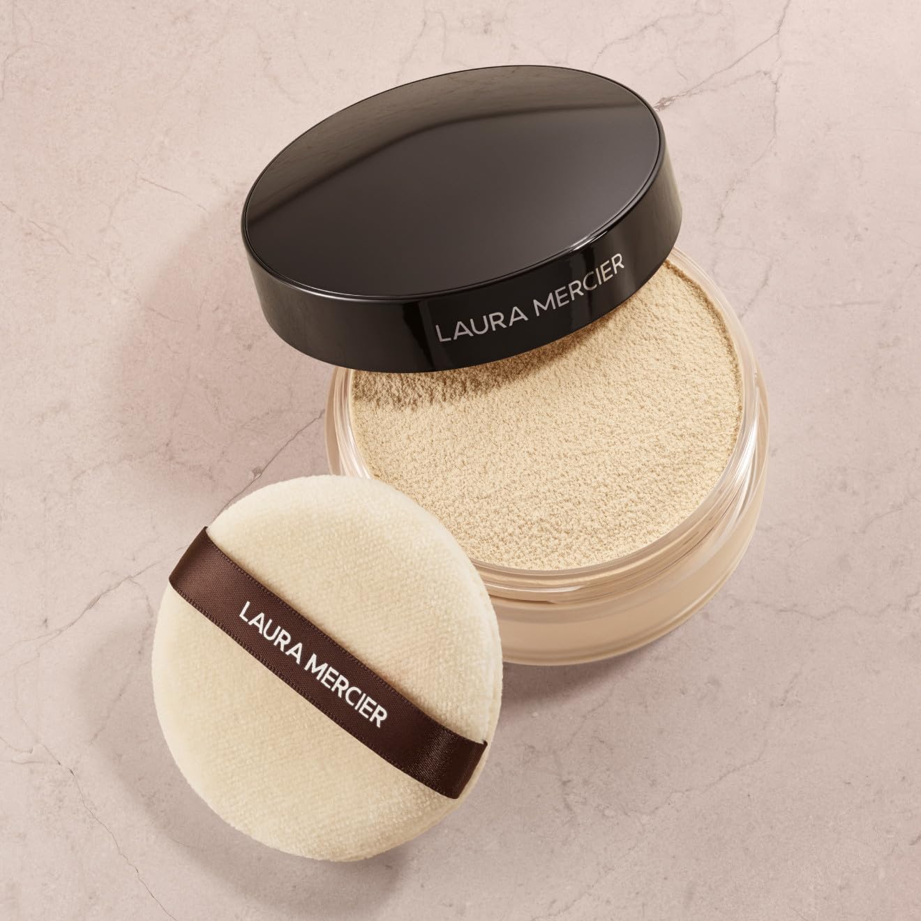 Laura Mercier velour puff held in hand to show 3.15" size for targeted coverage
