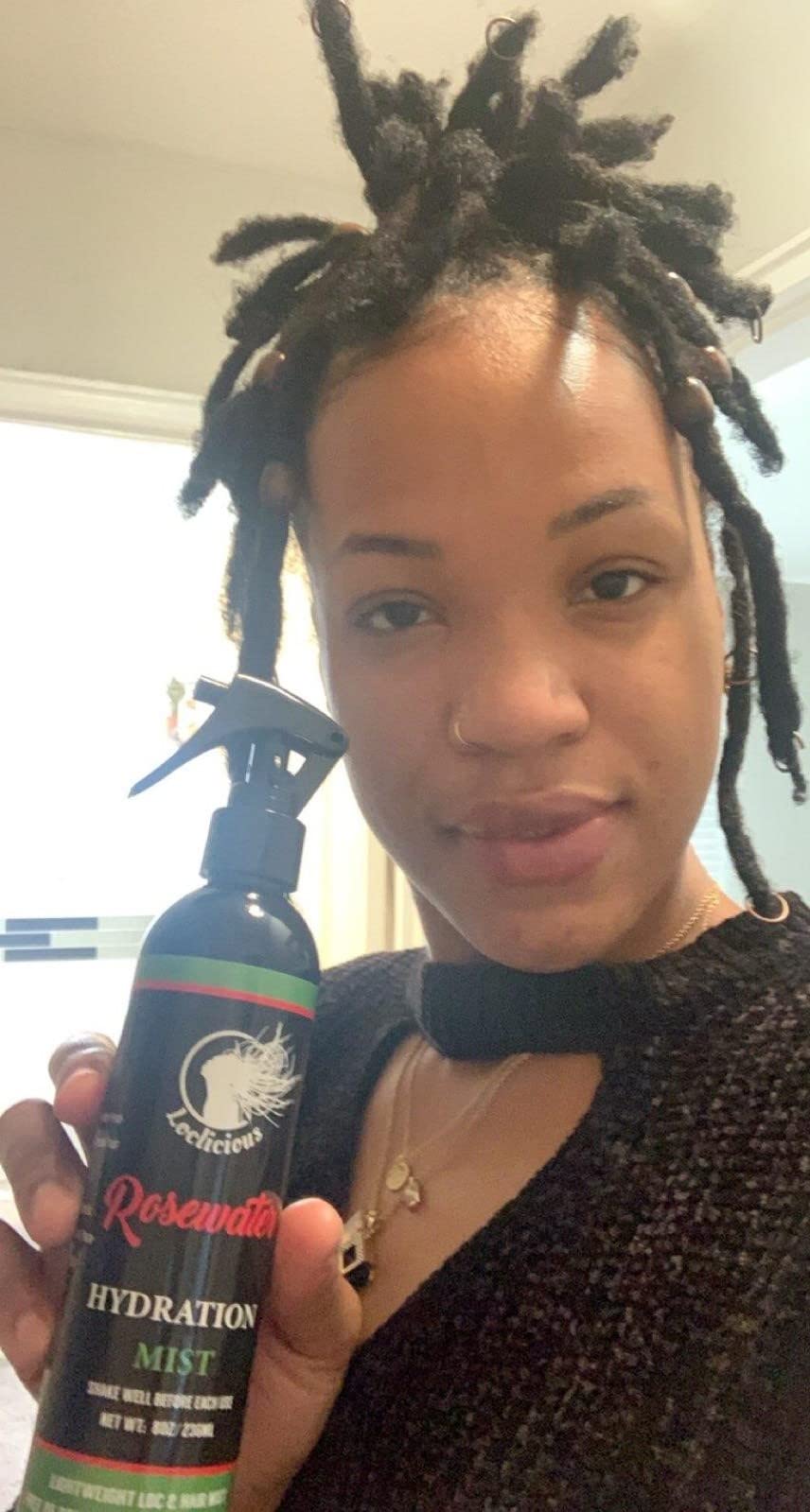 Hand holding LOCLICIOUS 8oz bottle to show size and portability for on-the-go moisturizing