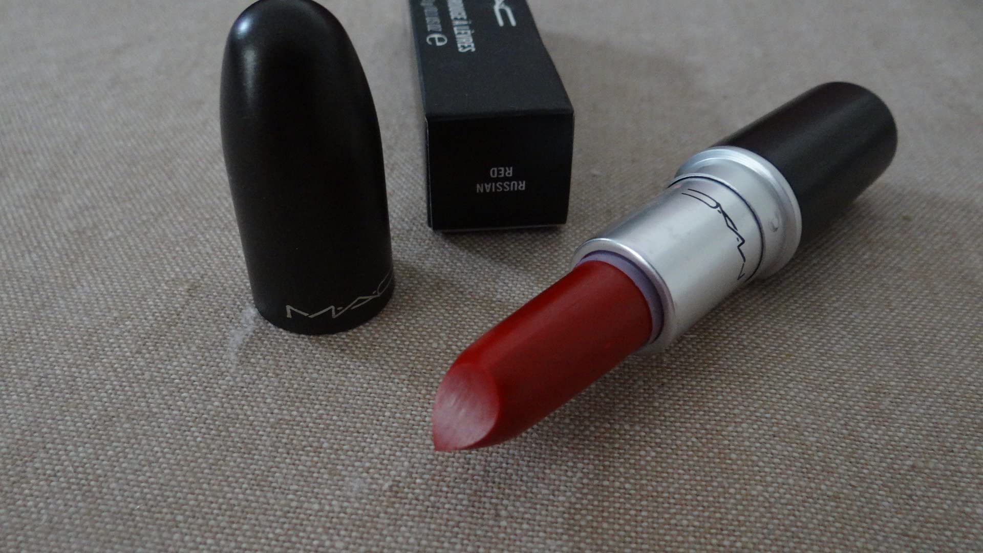 MAC Russian Red beside coin for scale indicating compact 0.1 oz size