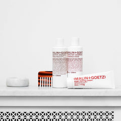 MALIN+GOETZ smoothing flyaways on dry hair for a polished, frizz-free finish