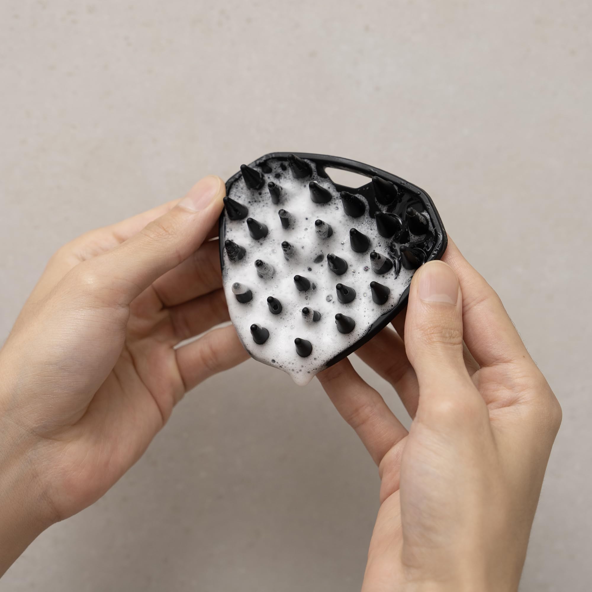 MANSCAPED Scalp Buffer held in hand for scale showing travel-ready size