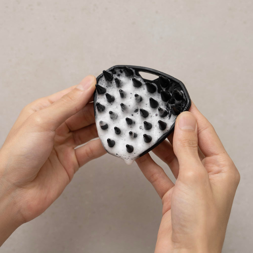 MANSCAPED Scalp Buffer held in hand for scale showing travel-ready size