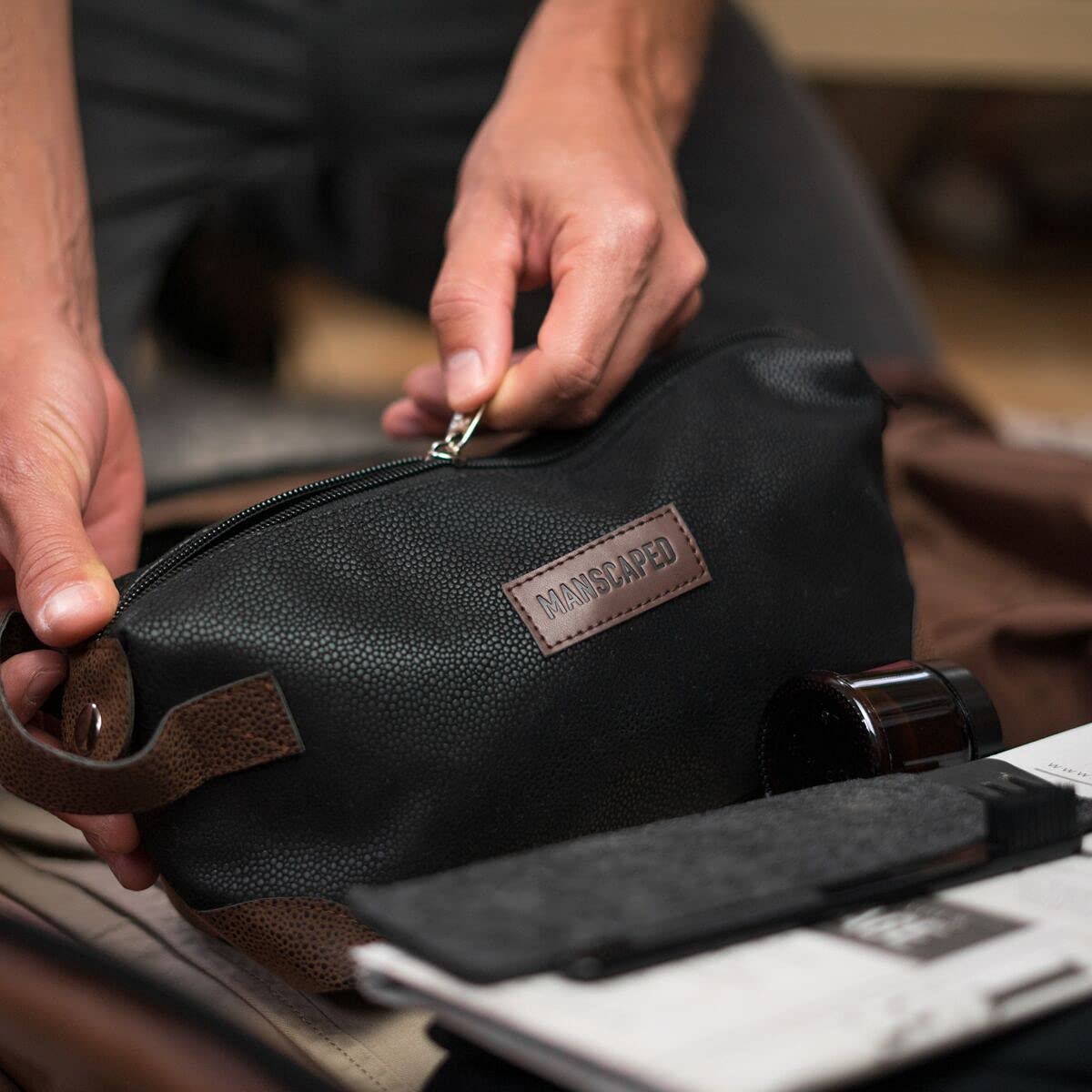 MANSCAPED bag open to lined interior displaying compartments — protects against spills