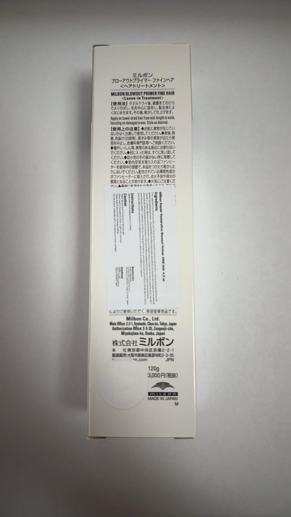 Milbon 4.2 oz tube next to a hand for size and portability reference
