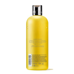 Molton Brown bottle in hand showing 10 fl. oz. size for scale and travel