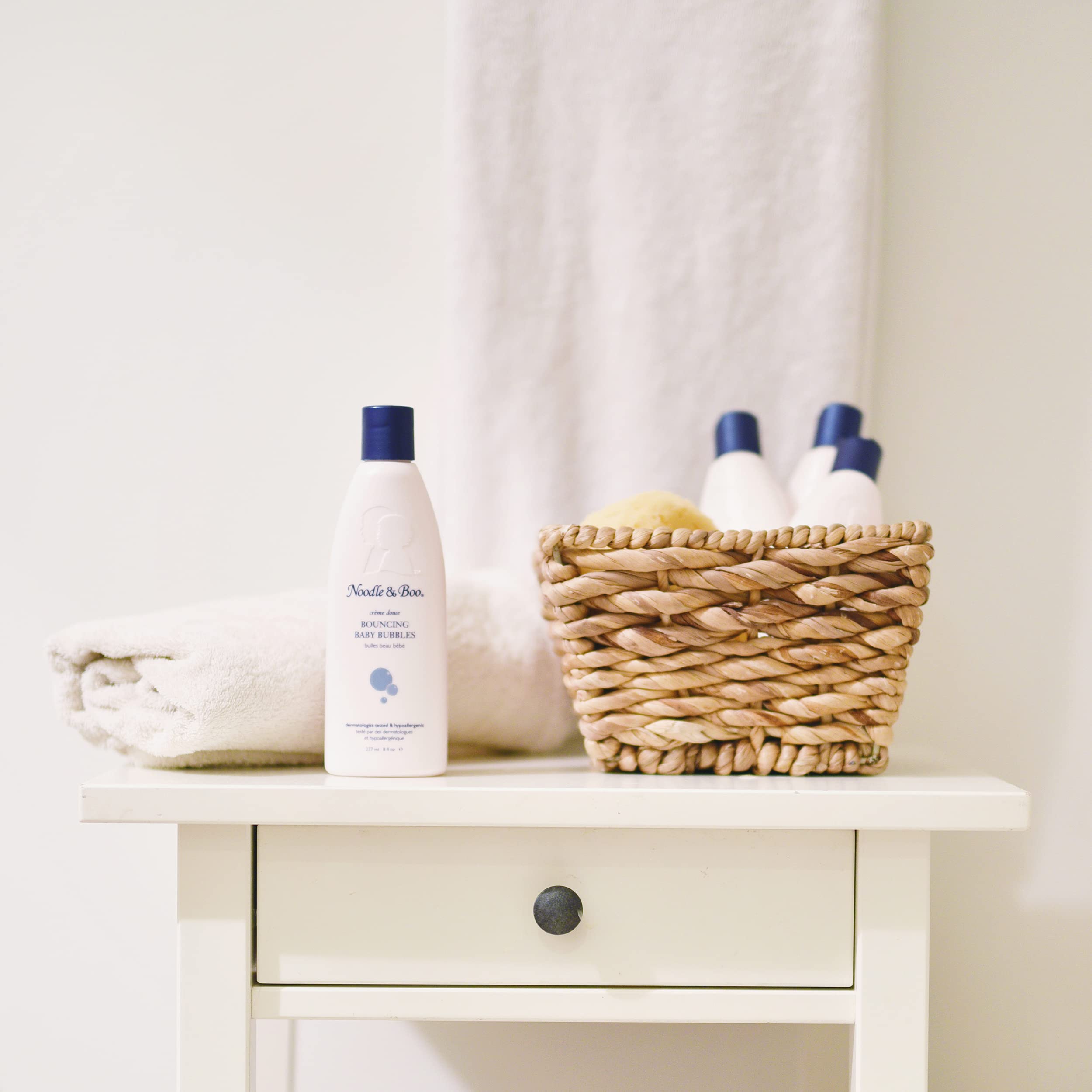 Noodle & Boo parent pouring bubble bath under running tap for safer bath time