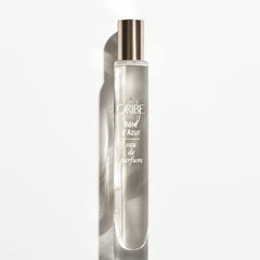 ORIBE atomizer in hand beside passport demonstrating travel-friendly convenience
