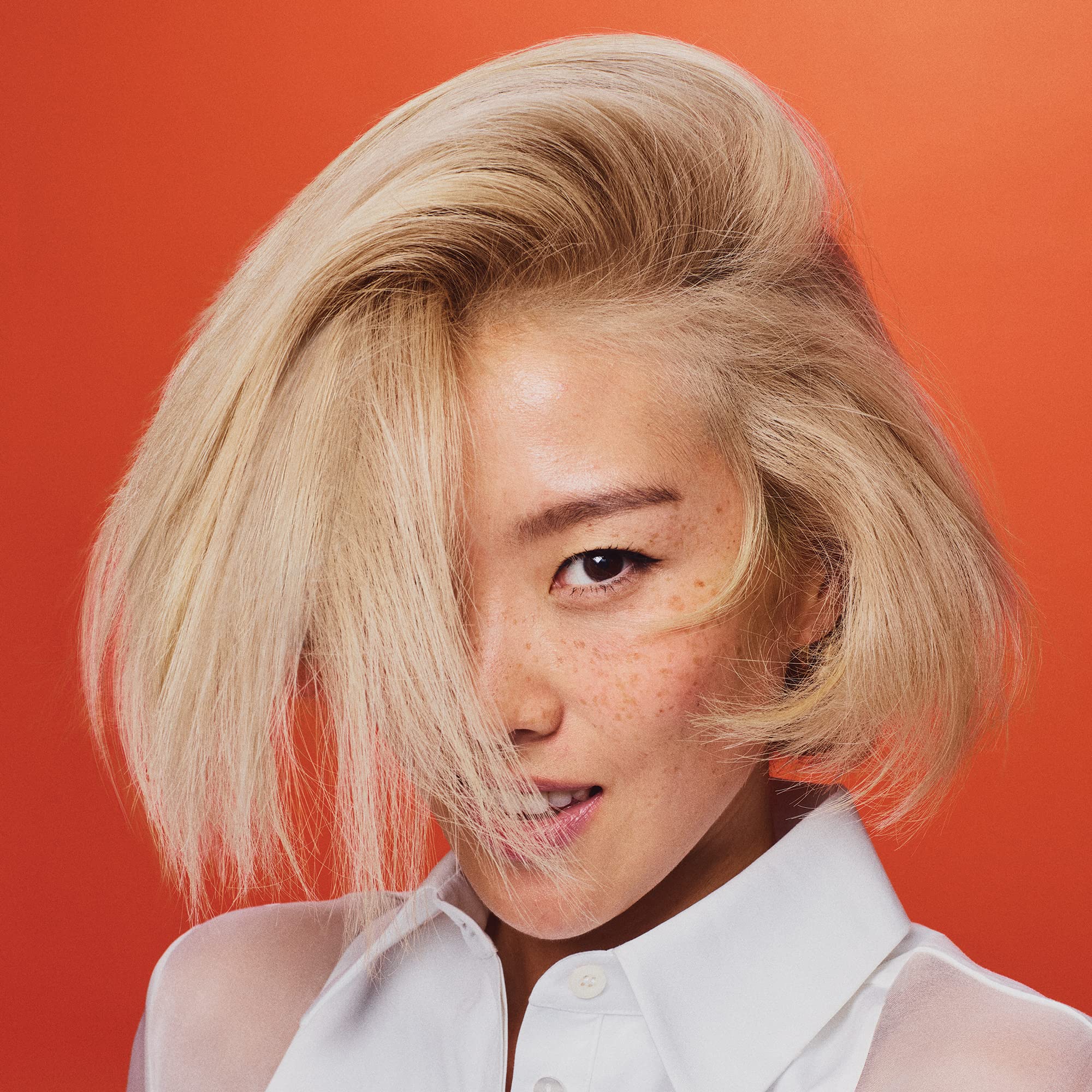 Oribe shampoo next to blonde model hair showing brighter, cooler results
