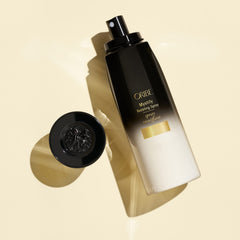 Oribe Mystify mist spraying from nozzle demonstrating lightweight texture and quick detangling benefit