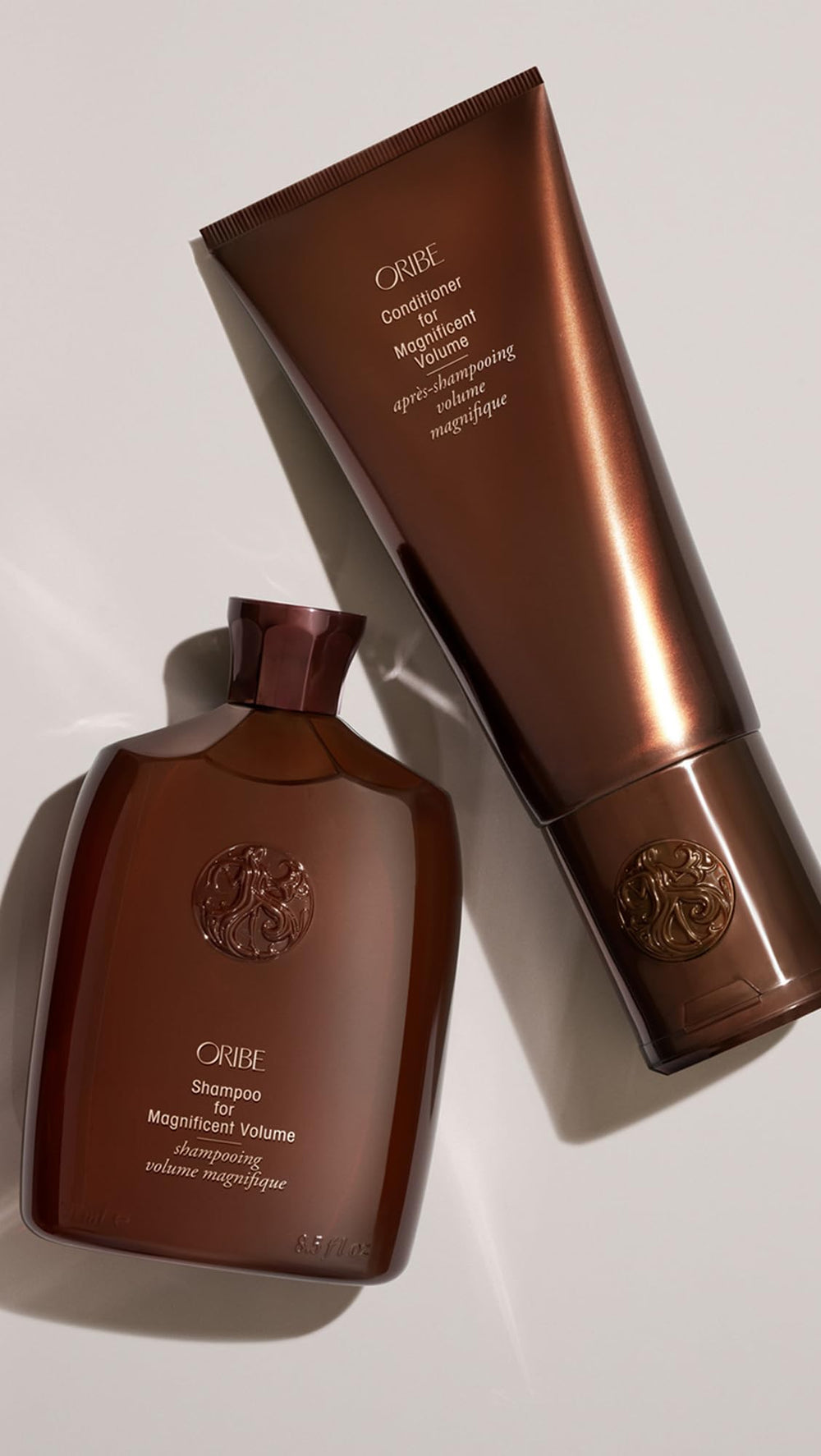 Oribe 6.8oz bottle beside common items to show size and pour amount for travel planning