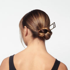 Model using Oribe Superfine to set a polished hairstyle with natural hold