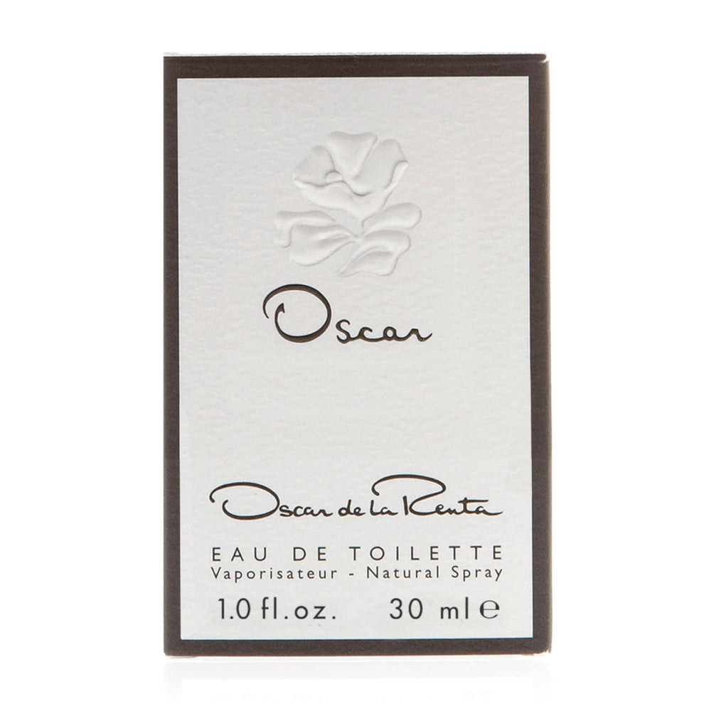 Oscar de la Renta bottle on wooden table ambient setting suggesting warm woods