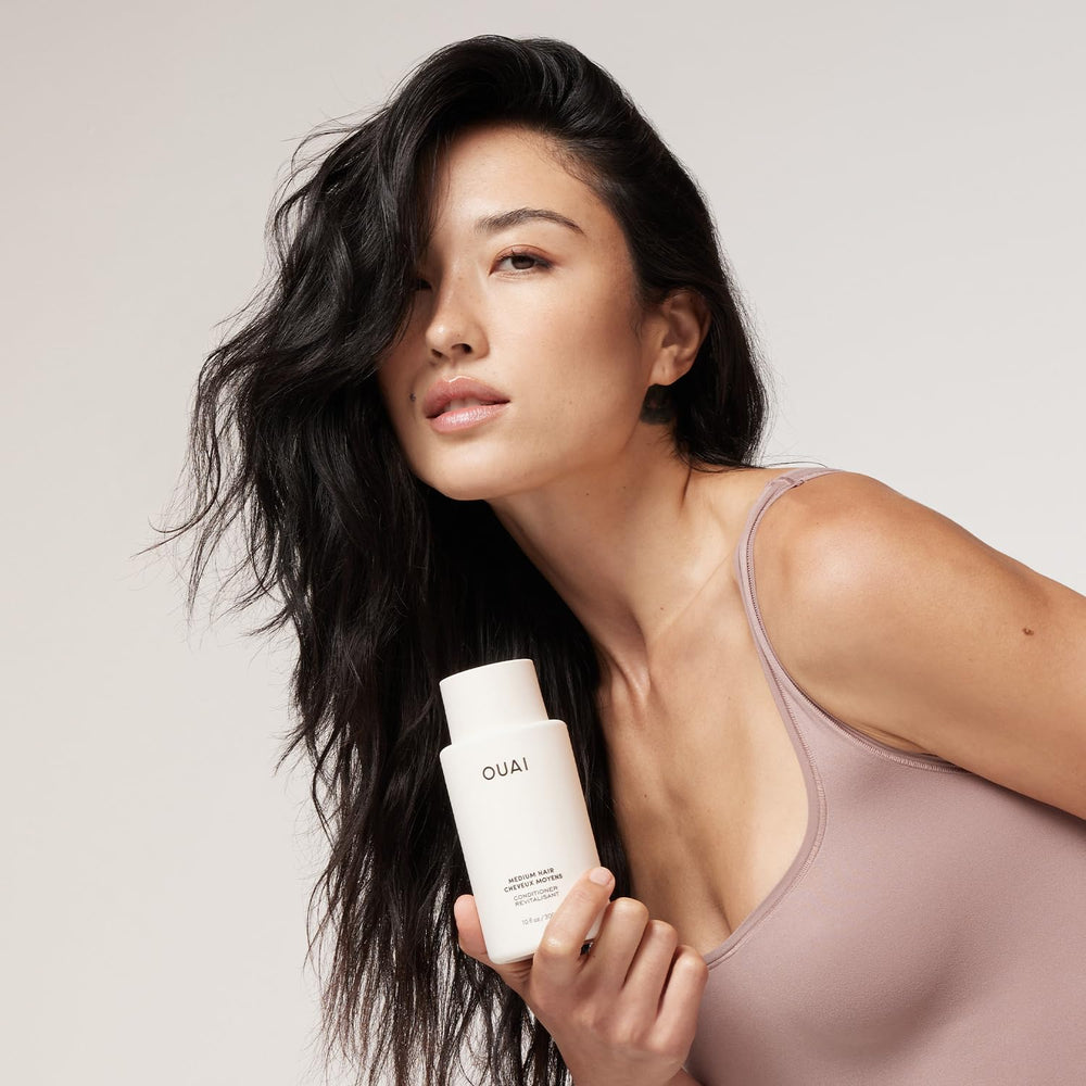 OUAI 3 oz bottle held in hand to show compact travel-friendly size