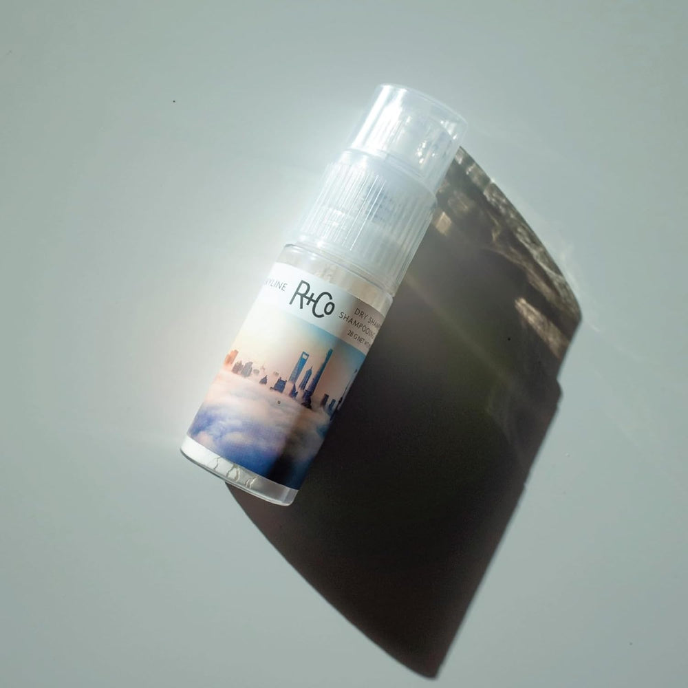 R+Co SKYLINE tin beside a hand to show 1.0 oz travel size convenience